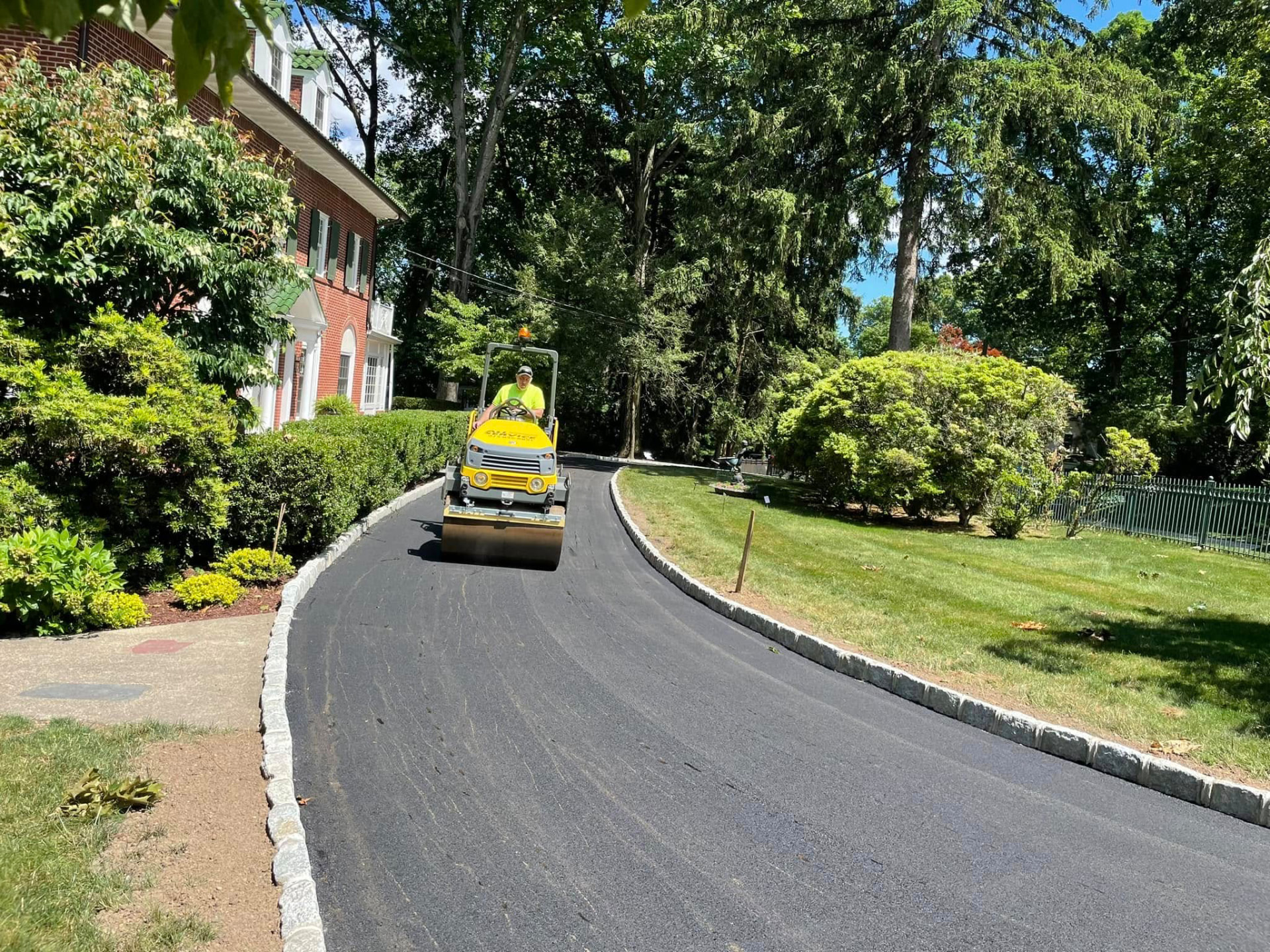 Roller compacting a newly paved curved residential asphalt driveway