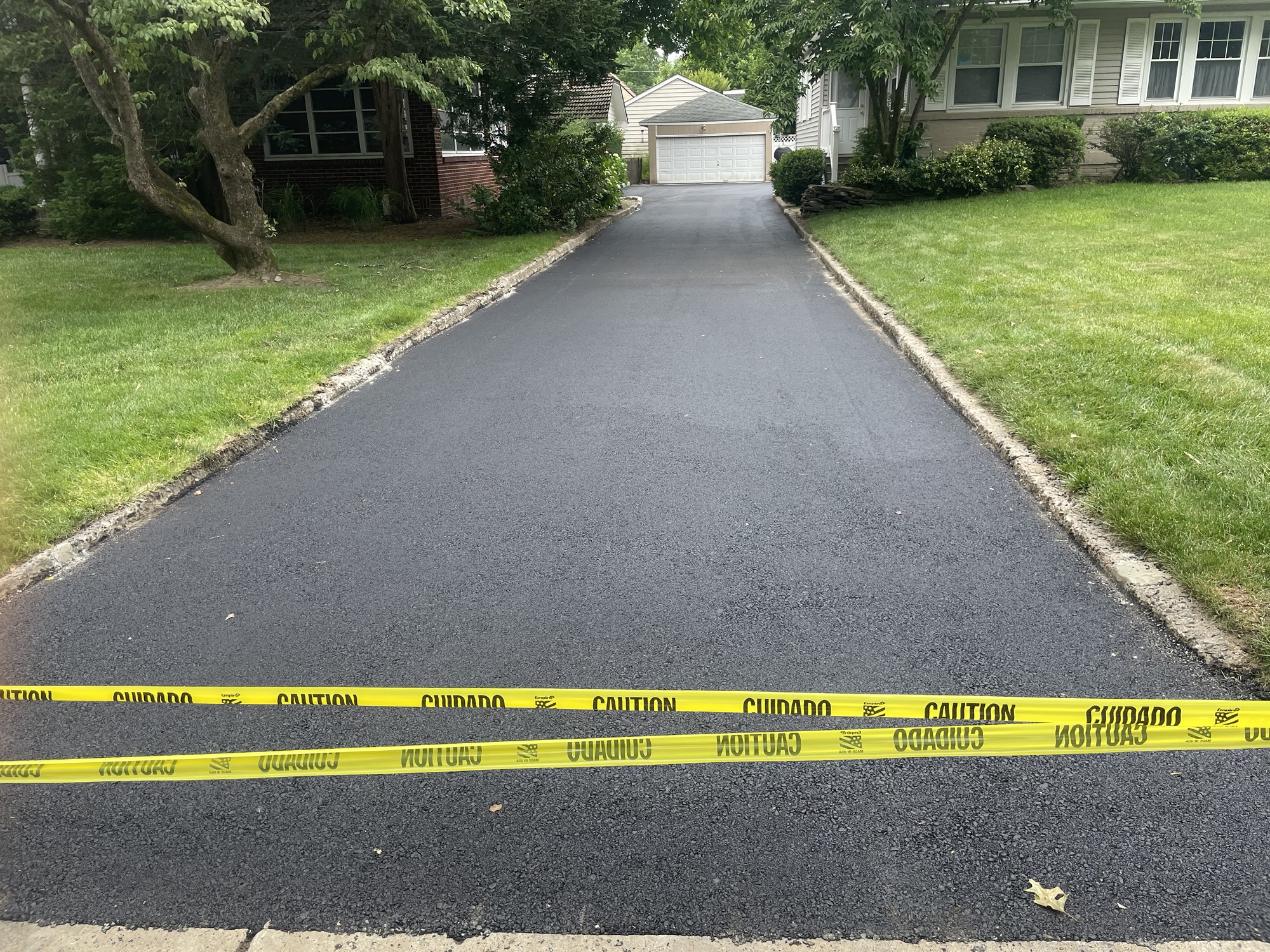 Completed long residential asphalt driveway with fresh black surface
